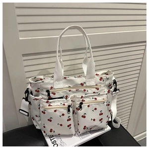 Détail du cabas blanc à cerises avec trois poches zippées et bandoulière amovible
