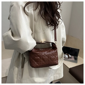 Detail of a brown quilted heart shoulder bag showing size and form on a model