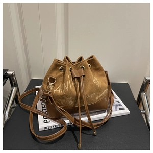 Detailed view of brown bucket bag with artistic script embroidery and drawstring closure