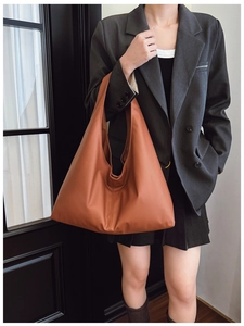 Brown oversized minimalist tote bag in soft faux leather shown on a shoulder