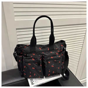 Détail du sac cabas en nylon noir avec imprimé cerises et multiples poches zippées