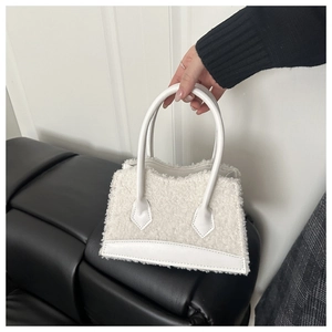 Detail view of white lamb-fleece handbag with leather handles and trapezoidal texture