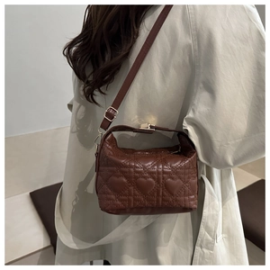 Detail of dark brown quilted heart pattern shoulder bag with gold buckle adjustment