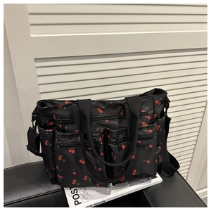 Détail du sac cabas en nylon noir avec imprimé cerises et quatre poches zippées