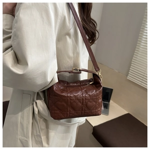 Deep brown quilted crossbody bag with heart pattern and top handle worn by a model