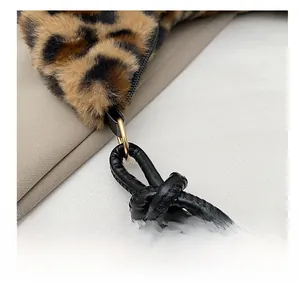 Dettaglio borsa in peluche leopardata con tracolla in pelle nera annodata e anelli dorati