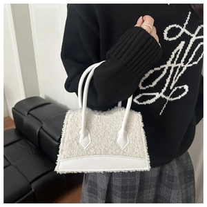 Detail of white faux fur tote bag with leather handle held by model in casual style
