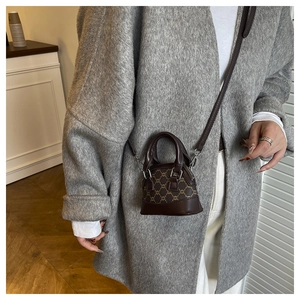 Detail of a mini brown crossbody bag with vintage shell pattern and silver metal zipper