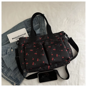 Détail du cabas noir en nylon avec imprimé cerise, poches et bandoulière réglable pratique