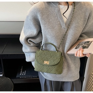 Detail of dark green quilted crossbody bag with gold twist lock and chain strap