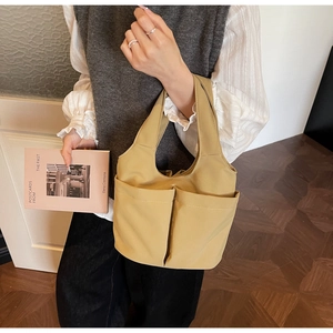 Détail du sac seau en nylon kaki avec deux poches avant dans une scène de style de vie