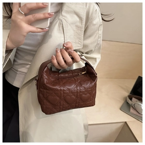 Detailed view of dark brown tote featuring quilted heart patterns and shiny texture