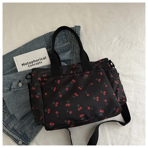 Détail du sac cabas noir à imprimé cerise avec poche zippée et bandoulière