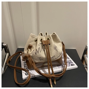 Detail of canvas bucket bag with brown leather trim and stylish letter print
