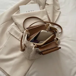 White faux fur bucket bag with brown leather trim and shoulder strap showing interior capacity