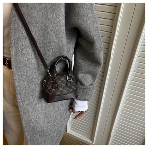 Detailed view of mini shell bag with retro pattern and leather trim on a wool coat