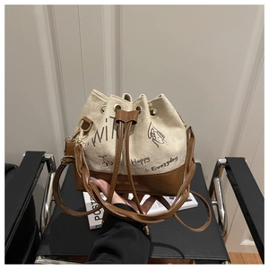 Detail of cream canvas bucket bag with brown leather base and cartoon print design