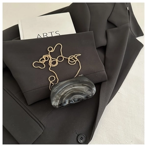 Macro view of grey marble texture evening clutch with a sleek gold ball chain strap