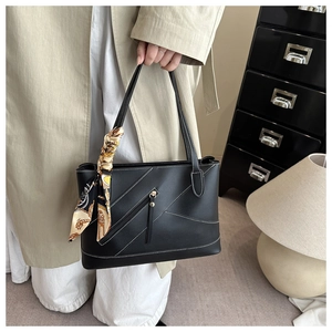 Detail of black tote bag with white contrast stitching and a patterned silk scarf handle