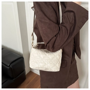 Detailed macro shot of the heart-shaped quilted pattern on the cream white faux leather bag