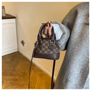 Detail of a dark brown shell-shaped crossbody bag with classic plaid pattern stitching