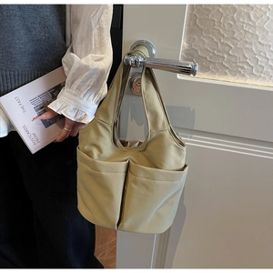 Vue détaillée du sac seau en nylon kaki avec deux poches avant suspendu à une porte