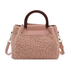 Pink faux shearling crossbody tote bag with brown handles and leather strap for winter fashion
