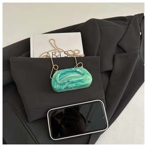 Detail of green and white marble resin clutch bag with elegant gold chain strap