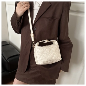 Close-up of white quilted bucket bag with heart stitching and gold hardware details
