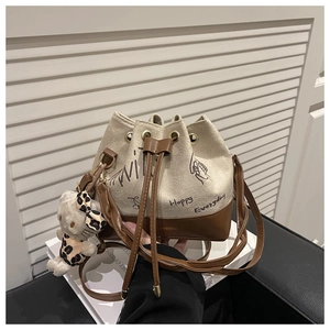 Detail of canvas bucket bag with leather trim and decorative plush kitten charm