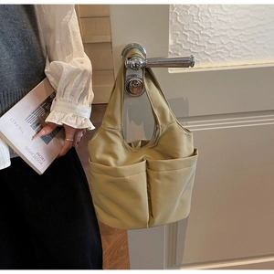 Gros plan du sac fourre-tout en nylon kaki clair avec grandes poches avant sur une porte