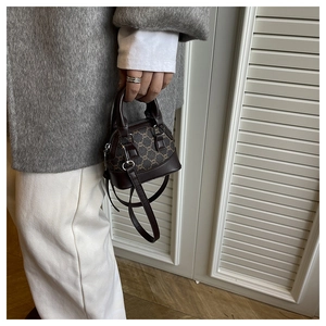 Detail of a vintage mini shell bag featuring dark brown monogram texture and leather handle