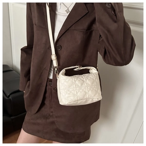 Detail of heart-quilted pattern on cream crossbody bag with gold hardware accessories