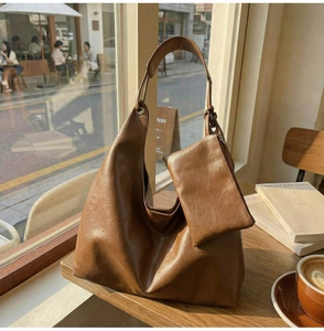 Detail of soft brown faux leather tote bag with matching inner pouch on wooden table