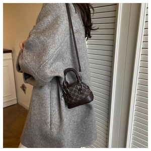Détail du mini sac rétro à motifs porté en bandoulière sur le côté par un mannequin