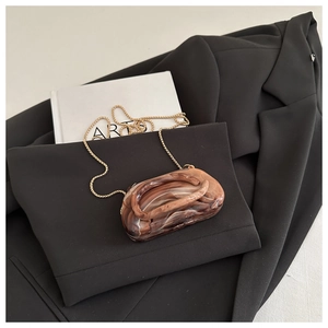 Detail of the amber marble texture shell clutch with golden metal chain strap