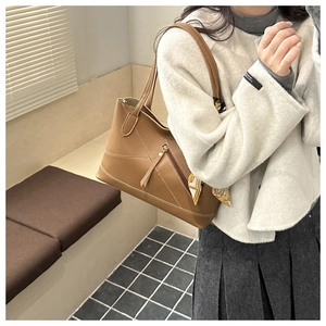 Detail of a brown leather tote bag with geometric stitching and a floral silk scarf handle