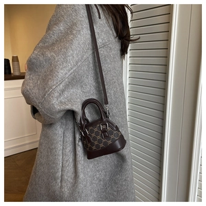 Detail view of mini retro shell bag with vintage pattern and dark brown leather accents