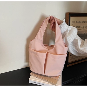 Vue détaillée du sac seau en nylon rose avec double poches avant et décor de livres