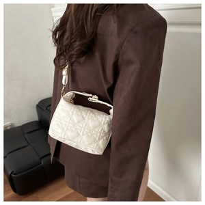 Detail of white heart-quilted shoulder bag worn by model in a minimalist interior setting