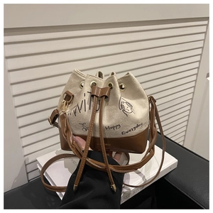 Detailed view of the drawstring closure and adjustable leather strap on a canvas bucket bag