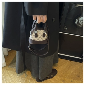 Detail of a mini monogram shell bag with brown leather trim held by a model