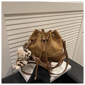 Close-up of brown bucket bag with hand-drawn prints and cute leopard plush bear charm