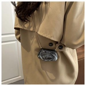 Crossbody wear of the marbled mini bag with golden chain on a khaki trench coat
