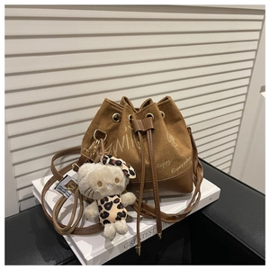 Detail of suede bucket bag featuring contrast colors and cute cat plush charm pendant