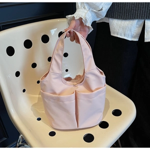 Vue détaillée du sac seau rose clair en nylon avec trois poches sur une chaise à pois