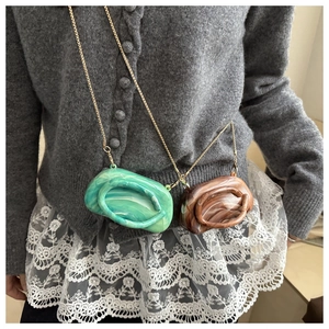 Detail of creative marble textured pebble clutch bags with gold metal chain straps