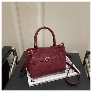Détail du sac à main en daim bordeaux avec bandoulière réglable et boucle métallique