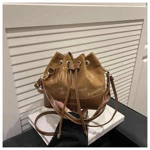 Close-up of brown bucket bag featuring creative white graffiti and mixed leather textures