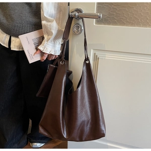 Detail of dark brown faux leather tote bag with natural texture and small zipper pouch